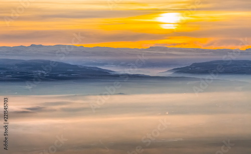 Mountains in the fog, haze. The Main Caucasian Range. Multicolored background. Mountains at sunset. Winter fog.