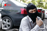 Masked thief in black balaclava trying to break into car with cctv camera viewfinder display. Criminal crime concept.