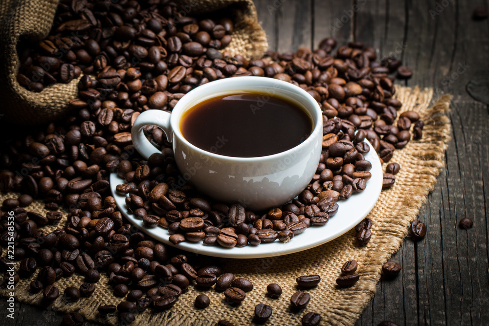 Coffee cup and beans on a rustic background. Coffee Espresso and a piece of cake with a curl. Cup of Coffee and coffee beans on table. Coffee cup and beans on a rustic background. Coffee Espresso and a piece of cake with a curl. Cup of Coffee and coffee beans on table.