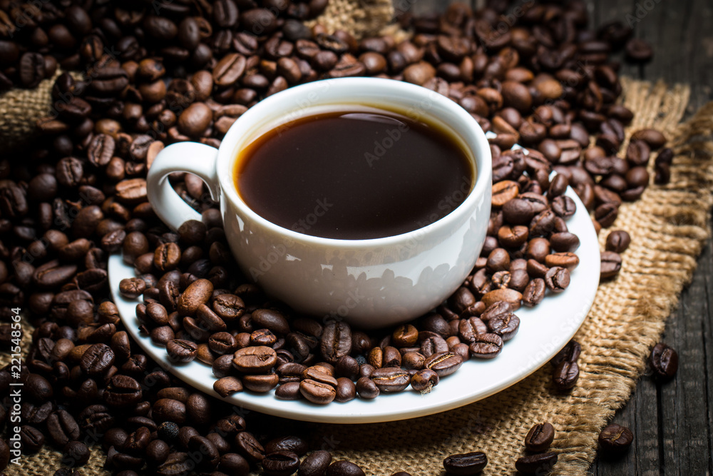 Coffee cup and beans on a rustic background. Coffee Espresso and a piece of cake with a curl. Cup of Coffee and coffee beans on table. Coffee cup and beans on a rustic background. Coffee Espresso and a piece of cake with a curl. Cup of Coffee and coffee beans on table.