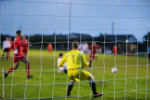 View from behind a footbal goal where the players are out of focus