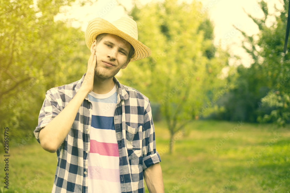 young male happy smiling farmer in hat and casual shirt in countryside natural farm a