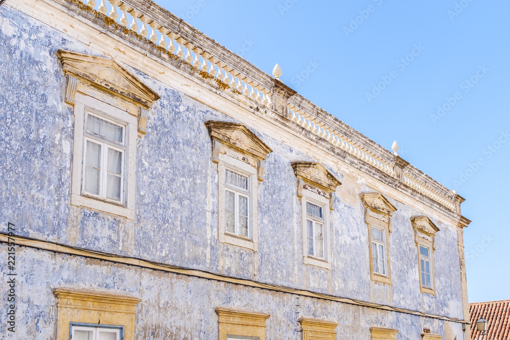 Naklejka premium Facade of a faded painted building in Portugal with roof top balustrade