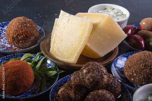 Set collection of cheese and snacks.  Belper knolle, olives, tzatziki sauce over on deep blue black background. photo