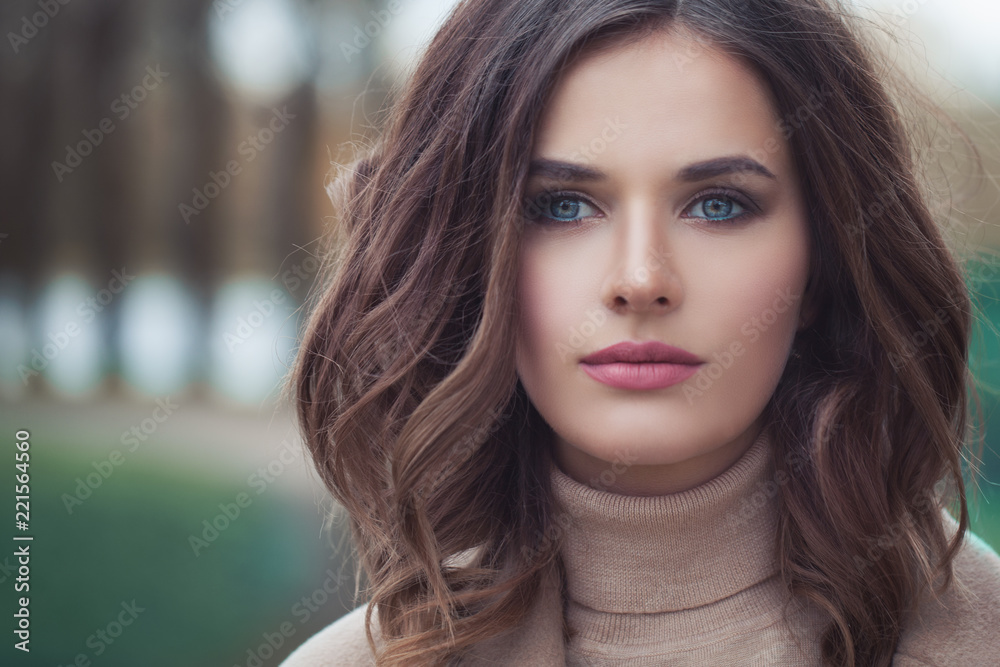 Young woman with wavy hair and makeup outdoor, face closeup Young woman with wavy hair and makeup outdoor, face closeup