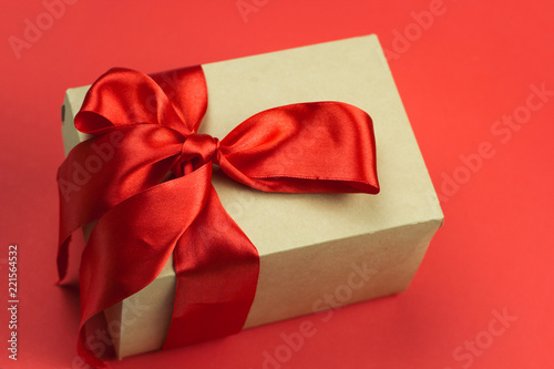 gift box with red satin ribbon on a red background © dvulikaia
