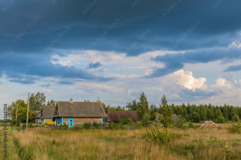 Countryside in Belarus, highr grass and old houses in the village bacground dramatic sky Countryside in Belarus, highr grass and old houses in the village bacground dramatic sky