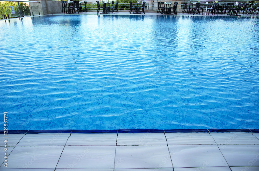 Obraz premium Chairs and tables next to a swimming pool. Luxury vacation concept