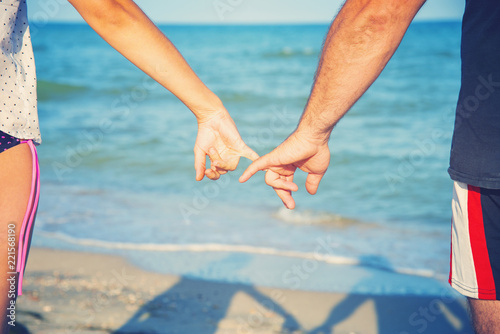A man holds a woman by the hand on the beach by the sea, the concept of family, love and peaceful life.