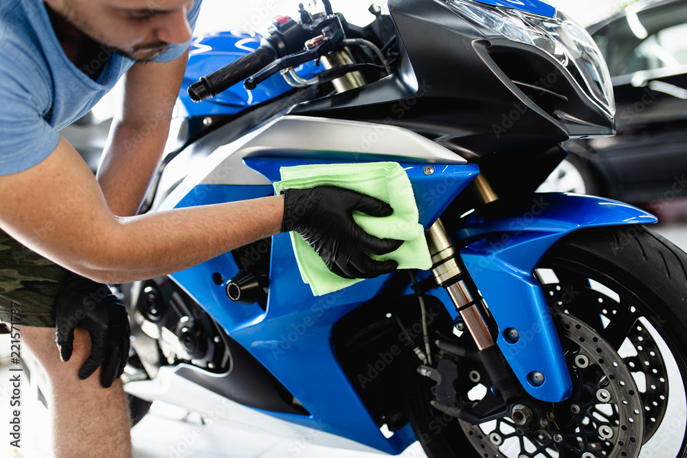 Fototapeta premium Człowiek czyszczenia motocykla z tkaniny. Selektywne skupienie.