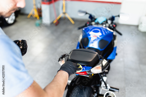 A man cleaning motorcycle with cloth. Selective focus.