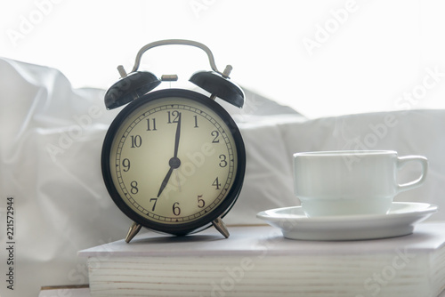 Alarm clock with book on bed in morning with sun light