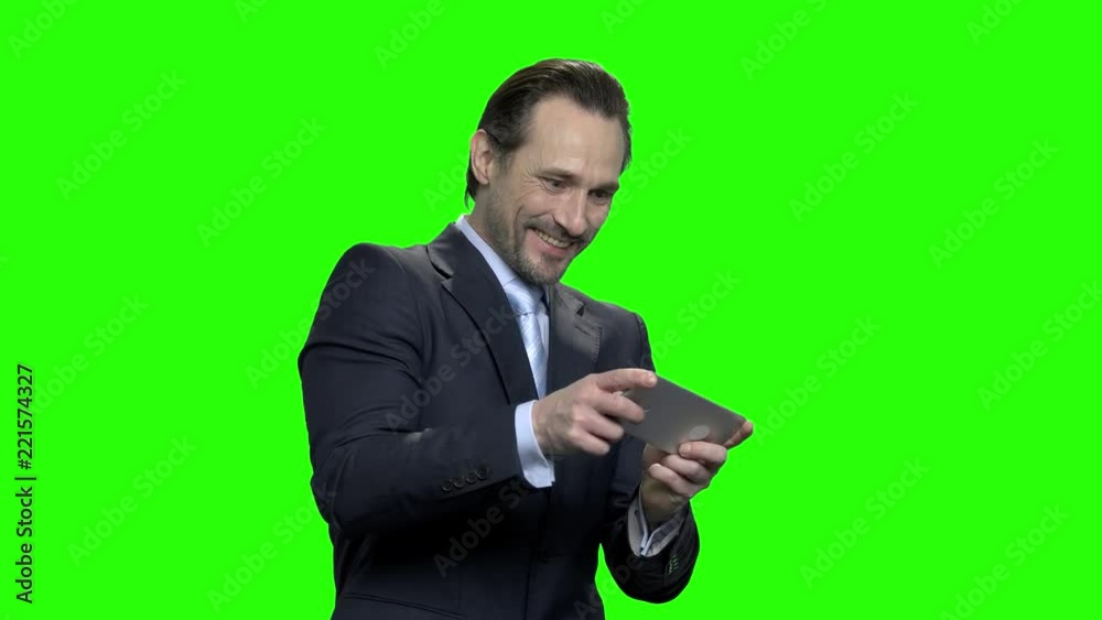 Mature excited business man plays video games on his phone. Green screen hromakey background for keying. Mature excited business man plays video games on his phone. Green screen hromakey background for keying.