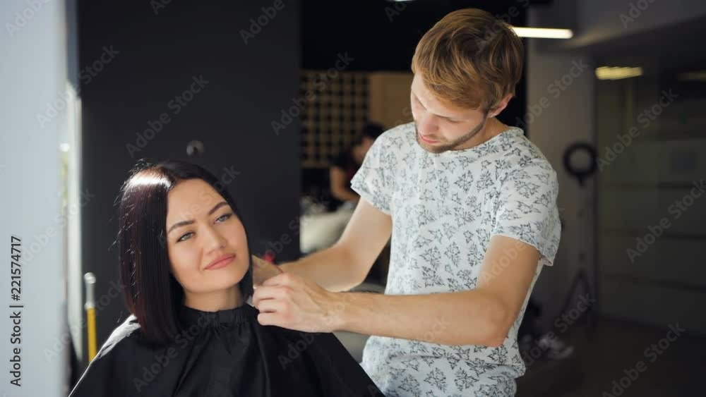 Beautiful brunette woman customer laugh in a beauty salon while talking to young male hairdresser. Making a cool hairstyle. Beautiful brunette woman customer laugh in a beauty salon while talking to young male hairdresser. Making a cool hairstyle.