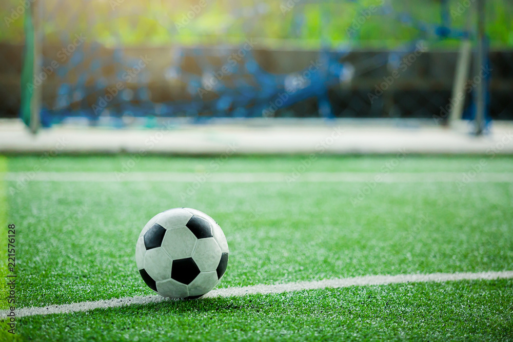 ootball on green artificial turf with blurry in front of goal.