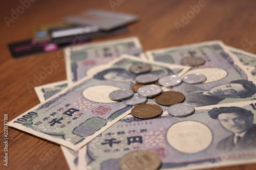 テーブルの上にばらまかれた日本のお金とクレジットカード 