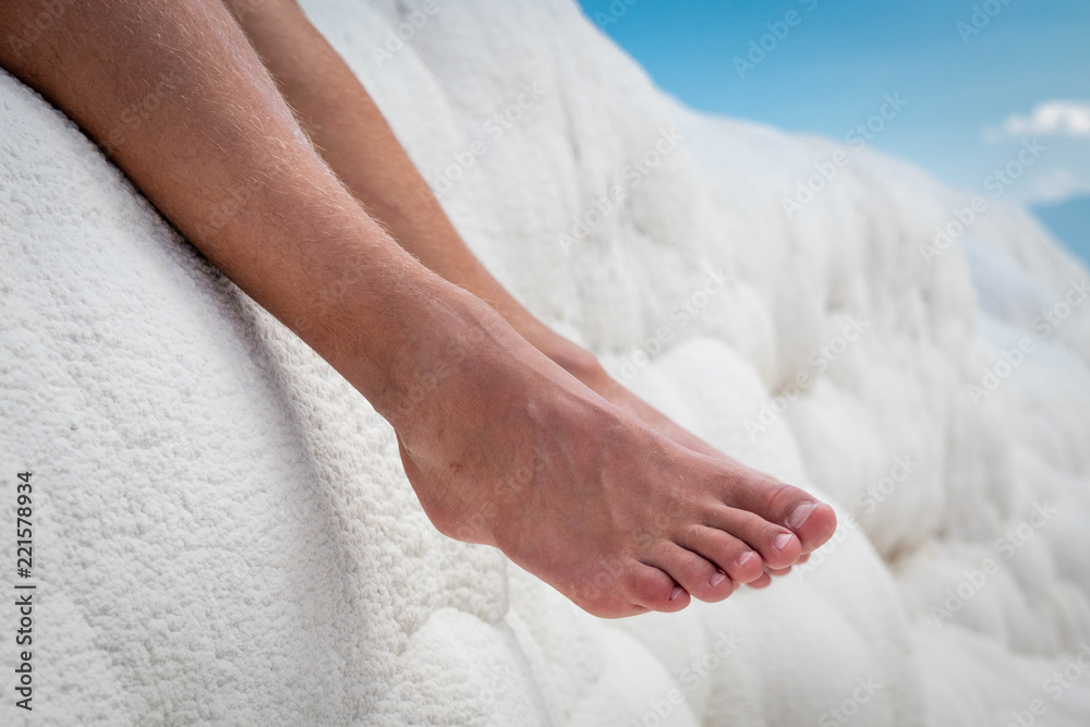Man legs in Natural travertine Pamukkale natural calcium carbide stone wall. Cotton castle in southwestern Turkey Man legs in Natural travertine Pamukkale natural calcium carbide stone wall. Cotton castle in southwestern Turkey