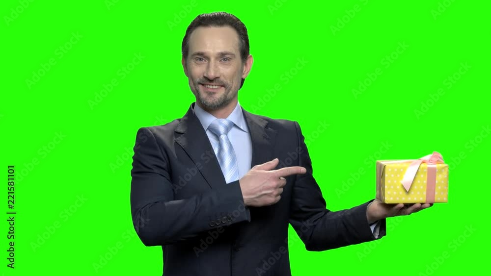 Portrait of man in suit pointing at present gift. Mature middle-aged caucasian businessman. Green hromakey background for keying. Portrait of man in suit pointing at present gift. Mature middle-aged caucasian businessman. Green hromakey background for keying.