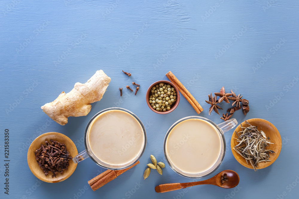 Traditional Indian tea masala with milk and spices on a blue background. Top view. Copy space