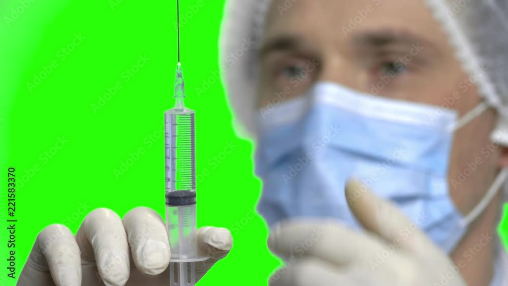 Doctor with syringe. Close up, doctor in medical mask ready to make injection. Green screen hromakey background for keying. Doctor with syringe. Close up, doctor in medical mask ready to make injection. Green screen hromakey background for keying.