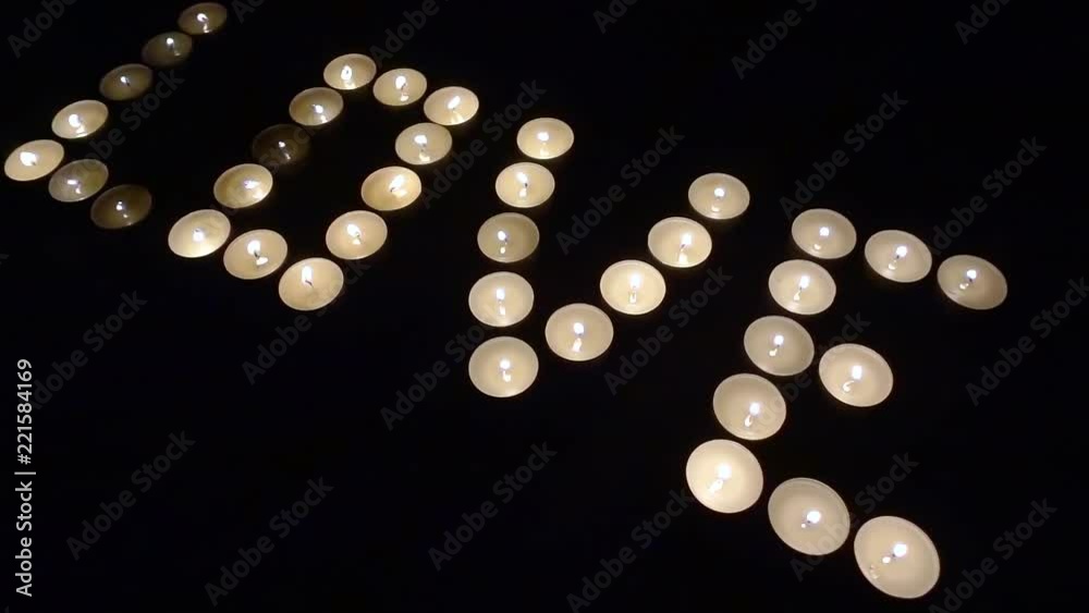 burning candles are arranged on black background in dark room in shape of word love, flames are flickering burning candles are arranged on black background in dark room in shape of word love, flames are flickering