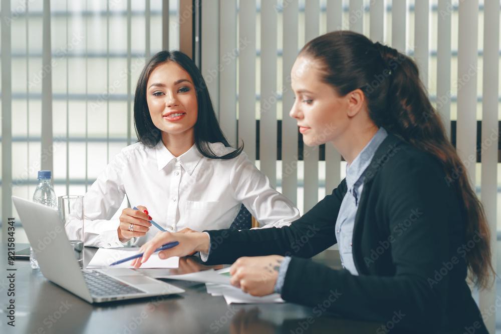 Women looking financial documents in laptop at table Women looking financial documents in laptop at table