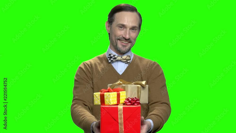 Portrait of a happy caucasian man giving gift boxes on camera. Green screen hromakey background for keying. Portrait of a happy caucasian man giving gift boxes on camera. Green screen hromakey background for keying.