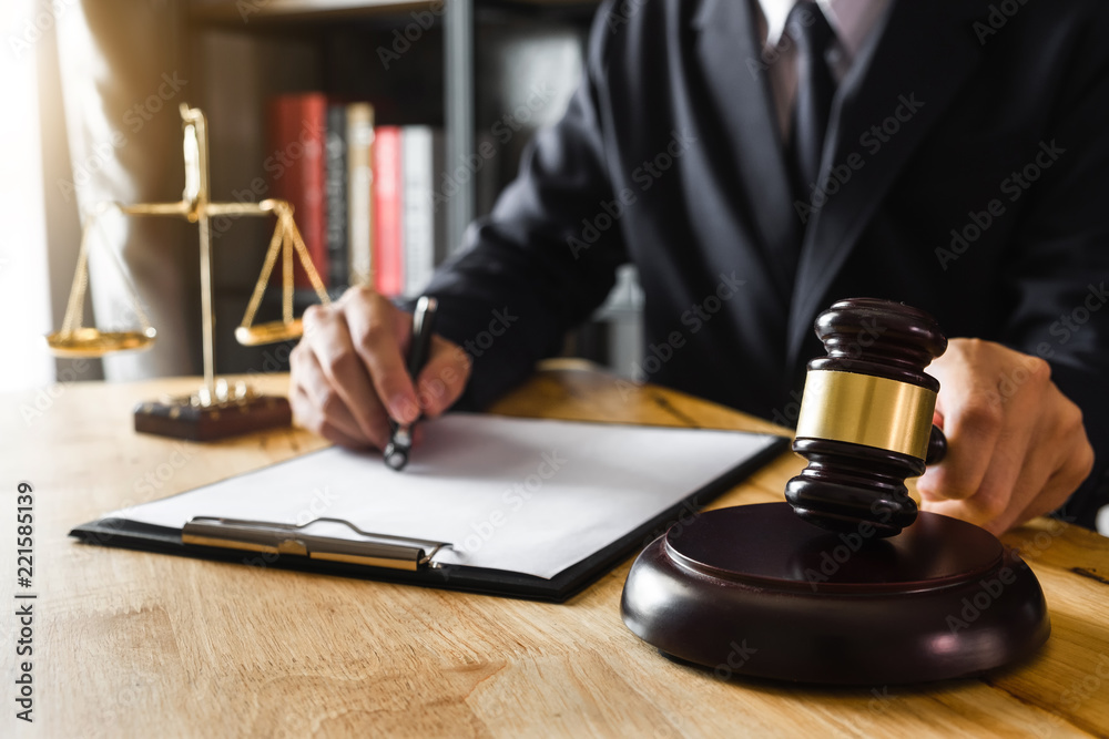 Justice and law concept.Male judge in a courtroom with the gavel,working with,digital tablet computer docking keyboard, eyeglasses,on wood table Justice and law concept.Male judge in a courtroom with the gavel,working with,digital tablet computer docking keyboard, eyeglasses,on wood table