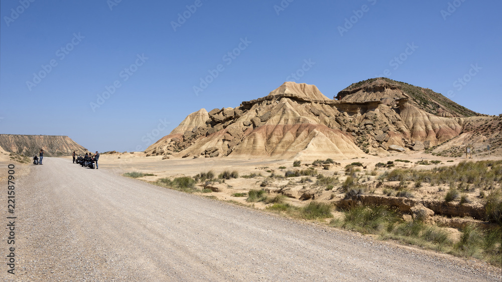 Spain, Bardenas Reales: Panorama view of famous natural semi desert sierra with Pisquerra rocky mountain chain, long road to the horizon, wide plains and blue sky in the background - concept travel.