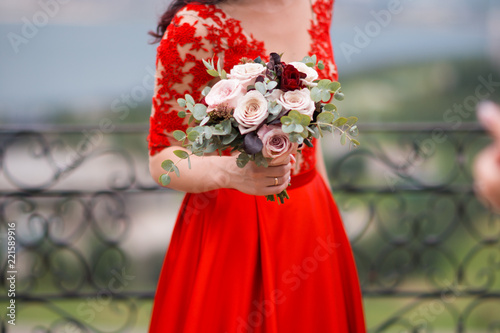 The bride in red dress is holding wedding bouquet