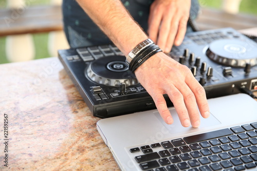 Hands of a professional DJ playing music using a mixer or controller and laptop.