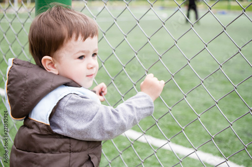 A boy 1,5 years old at the edge of a stadium watching football