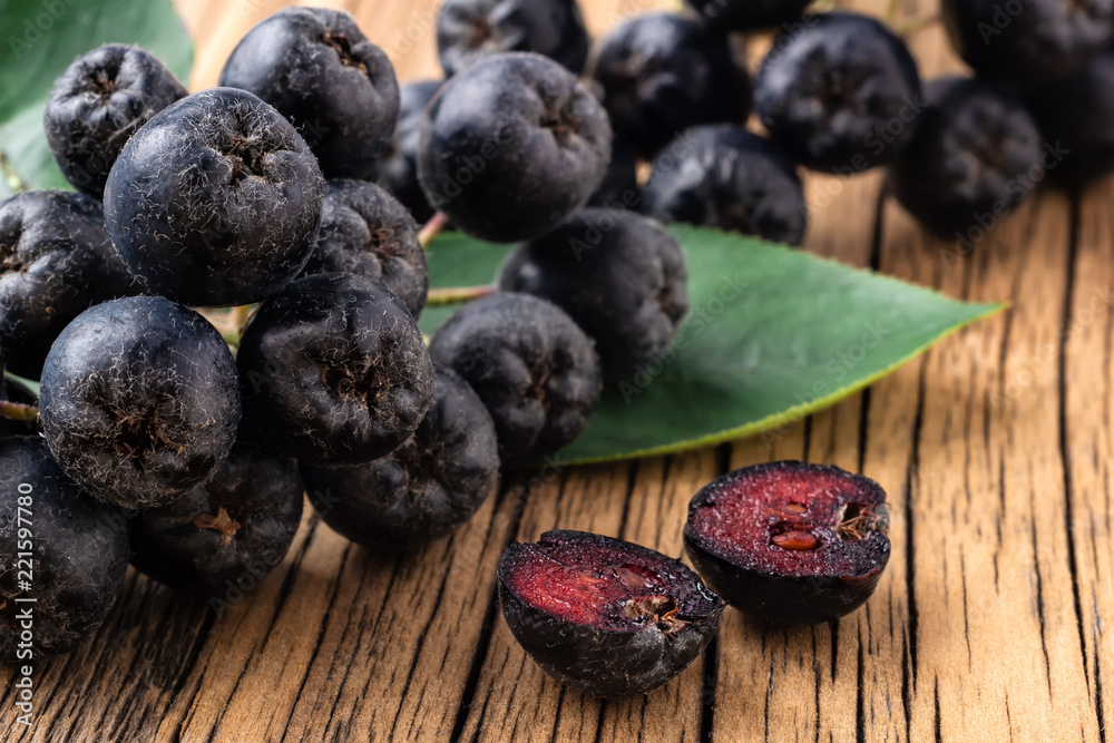 Berries of black mountain ash on a wooden background. Aronia melanocarpa. Therapeutic properties of black mountain ash. Super antioxidant. Berries of black mountain ash on a wooden background. Aronia melanocarpa. Therapeutic properties of black mountain ash. Super antioxidant.