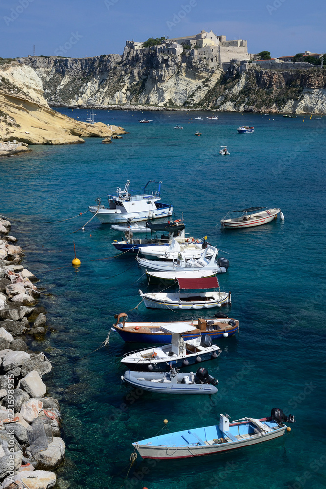 Puglia, Italy, August 2018, a stretch of Tremiti archipelago with some boats moored in San Domino port and the fortress of San Nicola island in background