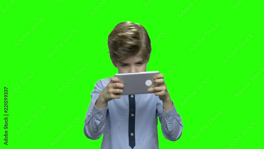 Excited kid playing game on smartphone. Green hromakey background for keying. Excited kid playing game on smartphone. Green hromakey background for keying.