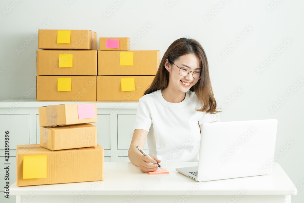 Online small business owner, Young business start up online seller owner using computer for checking the customer orders from email or website and preparing packages for product office equipment. Online small business owner, Young business start up online seller owner using computer for checking the customer orders from email or website and preparing packages for product office equipment.