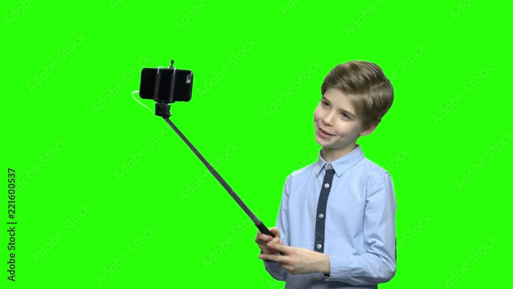 Cute caucasian boy with selfie stick posing for camera. Green hromakey background for keying. Cute caucasian boy with selfie stick posing for camera. Green hromakey background for keying.