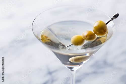 Martini cocktail with green olives on marble board. Close up.