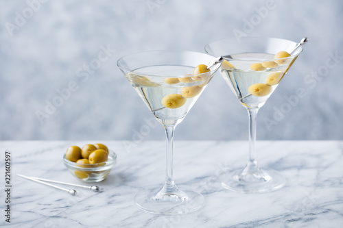 Martini cocktail with green olives on marble table background. Copy space.