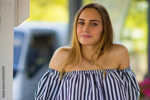 Portrait of a beautiful girl on the background of summer nature in the city