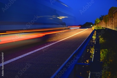 Evening shot of trucks doing transportation and logistics on a highway. Highway traffic - motion blurred truck on a highway motorway speedway at dusk