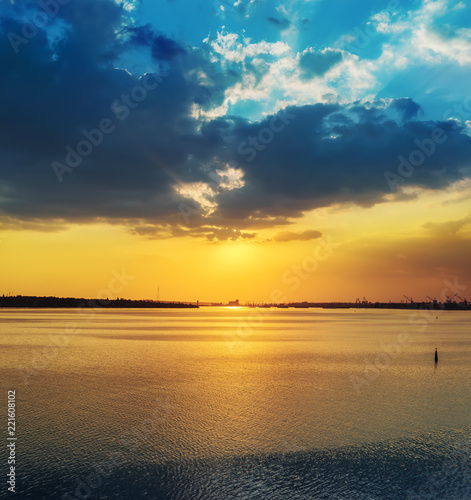 low dark dramatic clouds in sunset over river with reflections