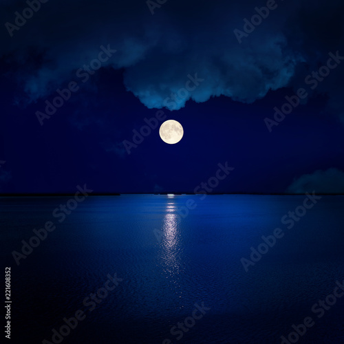 full moon in clouds over water