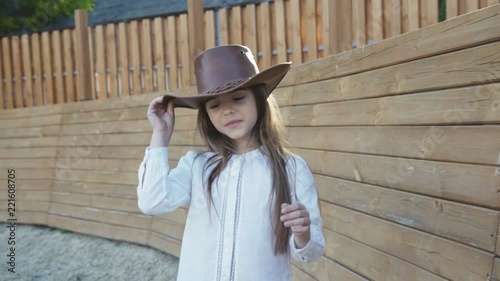 Cute little girl in hat walks and looks around with smile on the hippodrome photo