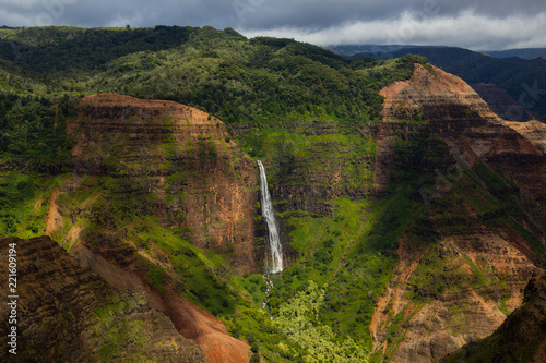 Waipoo Falls in Waimea Canyon in vivid greens and reds on the island of Kauai, Hawaii