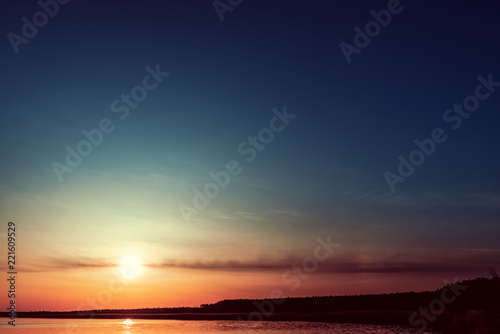 good orange sunset in dark blue sky over water