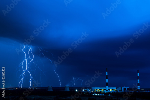 The cooling towers of thermal power station in the rainy night during the storm with the lightning