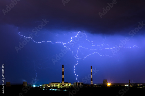 The cooling towers of thermal power station in the rainy night during the storm with the lightning