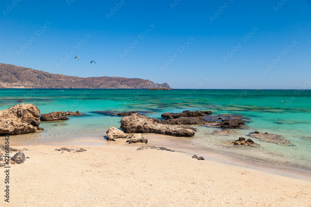 The famous beach of Elafonisi with kite surfers on background at southern Crete one of the most beautiful beaches of Greece. The famous beach of Elafonisi with kite surfers on background at southern Crete one of the most beautiful beaches of Greece.