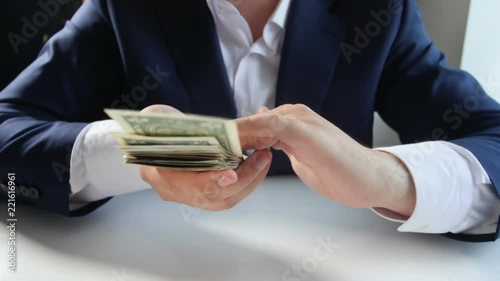 Slow motion footage of successful businessman throwing money from big stack of dollars